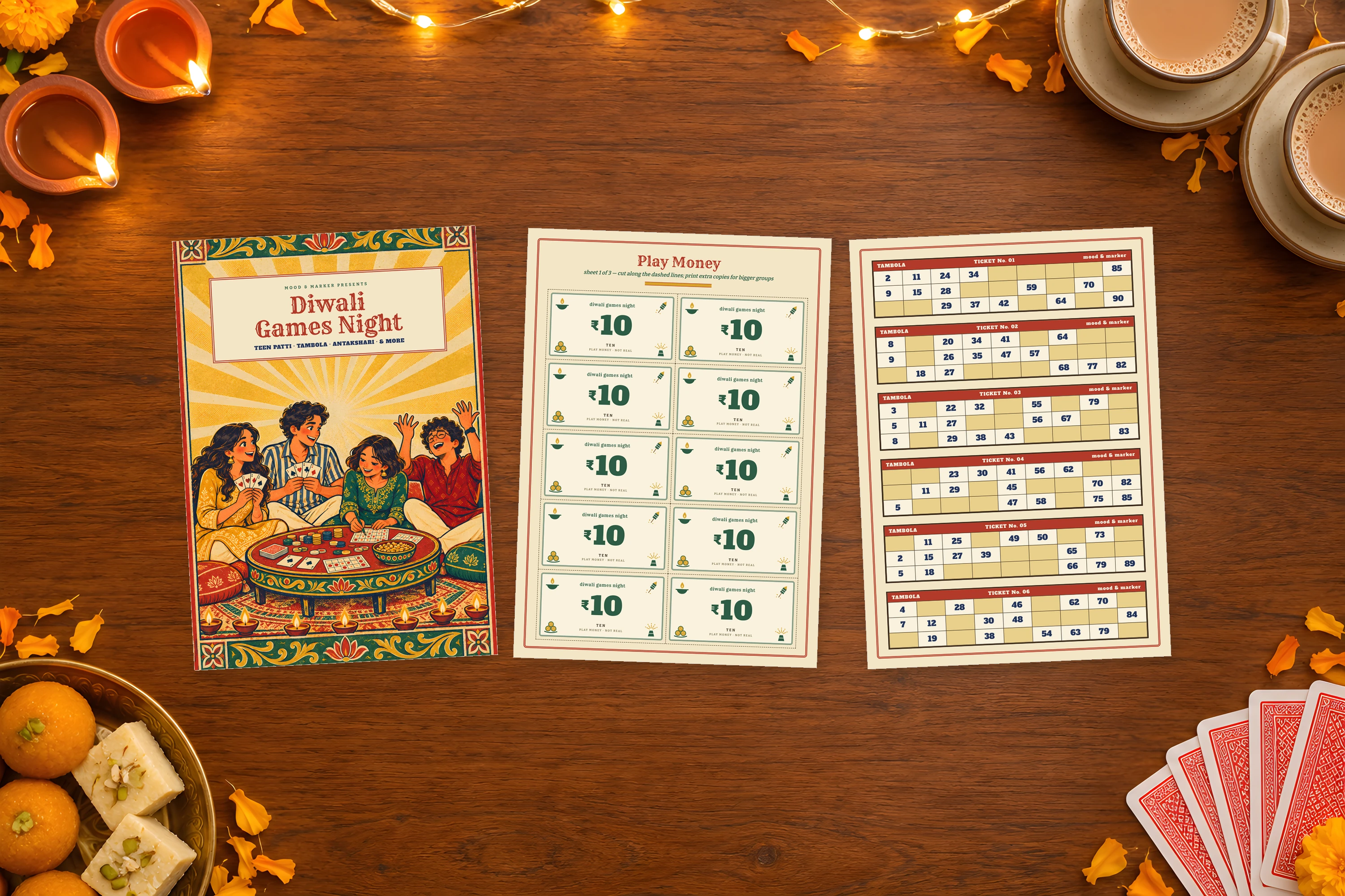 The cover, a sheet of play money and a Tambola sheet on a wooden table with diyas, chai and a pack of cards